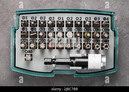 A set of metal power bits in a box on a gray background, for repair and maintenance Stock Photo