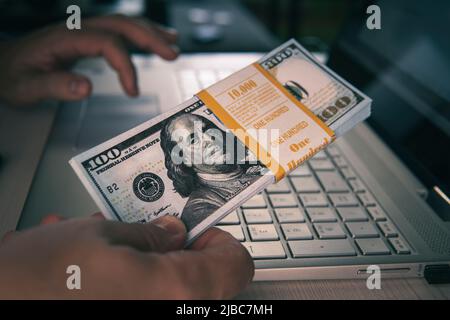10000 dollars banknotes on a laptop keyboard. concept of making money online, earning with the internet, passive income. earning money on the Internet Stock Photo