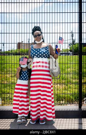 Posed portrait of a mother and her young daughter in matching outfits prior to the start of the Memorial Day Parade in College Point, Queens, New Yor. Stock Photo