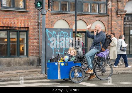 Copenhagen, Denmark - May 23 2022: Danish young father with children riding a cargo bike on a bike road in Christianshavn neighborhood in Copenhagen Stock Photo