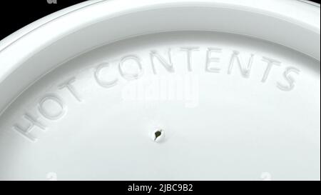 Disposable paper cup with white plastic lid, embossed "HOT CONTENS". Stock Photo