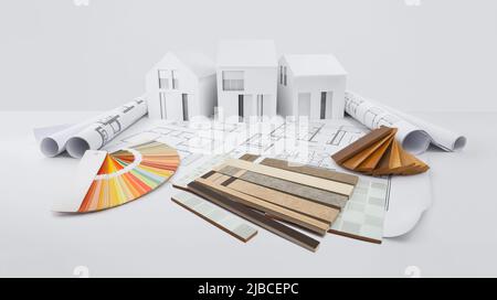 samples of marble tiles with sampler of wooden baseboards and colors swatches, on blueprint drawing with model of houses, interior design, finishing d Stock Photo