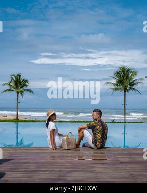 a couple of men and women relaxing by the pool during a luxury vacation in Thailand.  Stock Photo