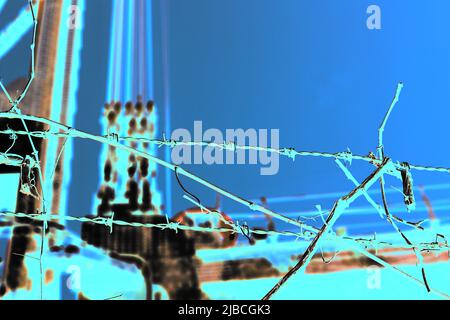 Razor sharp barbed wire fence protecting the industrial area in a bright blue color film negative. Stock Photo