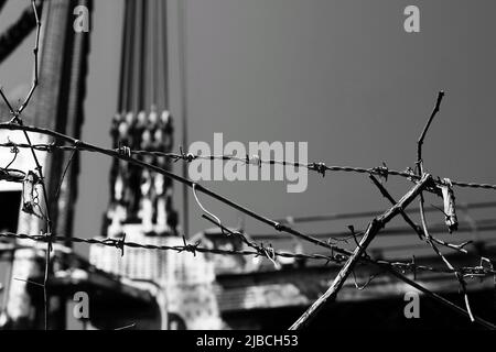 Razor sharp barbed wire fence protecting the industrial area in black and white. Stock Photo