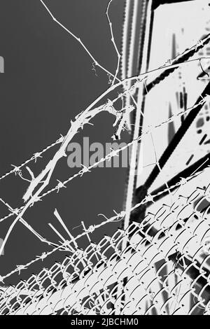 Razor sharp barbed wire fence protecting the industrial area in black and white high contrast. Stock Photo