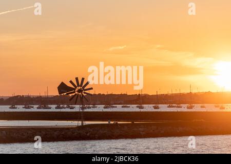 Sunset over Poole Harbour and Brownsea Island lagoon and wind-powered water pump, Dorset, England, UK Stock Photo