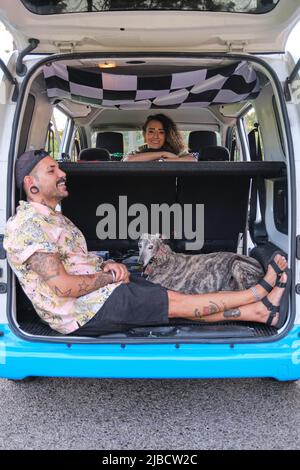 Young tattooed couple smiling with their dogs sitting in the back of the van. Stock Photo