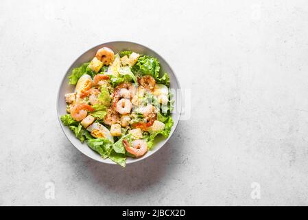Shrimp Salad. Healthy Seafood Caesar Salad with prawns and parmesan cheese on white stone background, top view, copy space. Stock Photo
