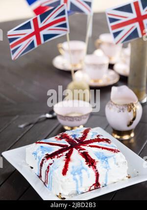 Concept Britishness,  British; bone china tea cups, union jacks, the flag of the UK, and cake as part of the Platinum Jubilee celebrations, Suffolk UK Stock Photo