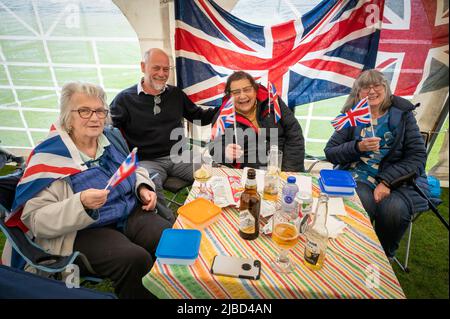 Willingham Cambridgeshire, UK. 5th June, 2022. People celebrate the Queen's Platinum Jubilee weekend in the rain at a picnic on the recreation ground. Lot's of people were determined to celebrate the occasion despite the drizzling rain, bringing their own picnics and enjoying a blues band, food stalls, bar and games. Credit: Julian Eales/Alamy Live News Stock Photo