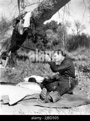 CLARK GABLE checks his rifle during Hunting Trip in April 1937 publicity for Metro Goldwyn Mayer Stock Photo