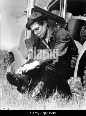 CLARK GABLE putting his boots on during Hunting Trip in April 1937 publicity for Metro Goldwyn Mayer Stock Photo