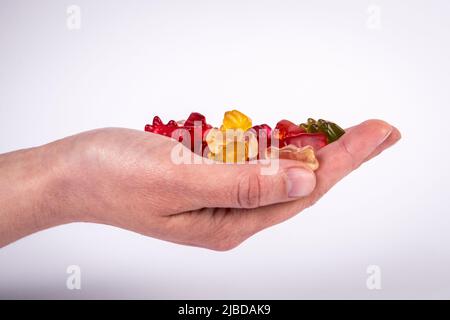 Red rubber candy bear in palm of woman on a white background. Stock Photo