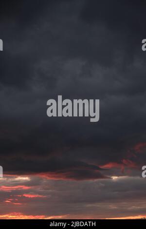 Thunderclouds with breaking rays sun at sunset Stock Photo