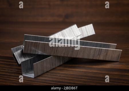 Metal staples for staple guns on a wooden texture background. Stock Photo