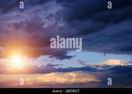 Thunderclouds with breaking rays sun at sunset Stock Photo