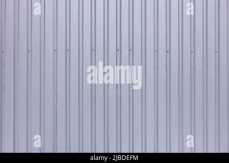 Background and texture of a gray profiled fence fixed with a row of metal screws. Stock Photo