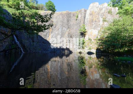 The waterfall of Babory rushes in an abyss of quiet and dark water. It is situated near the castle of Sailhant . France. Stock Photo