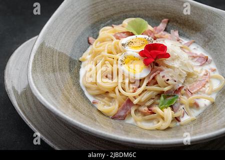 Spaghetti Carbonara with sauce, on a plate, on a dark background Stock Photo