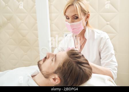 Female beauty therapist treating male face with anti-aging serum Stock Photo
