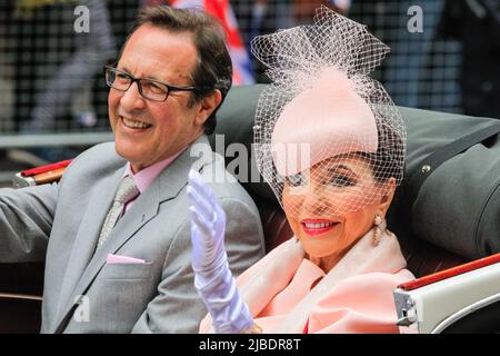 London, UK. 05th June, 2022. Actress Dame Joan Collins and husband Percy Gibson smile and wave from their open top vintage car. The Platinum Jubilee Pageant features 10,000 participants in four acts, 'For Queen and Country', a military parade, 'The Time of Our Lives', showing the 7 decades of the Queen's reign, including 150 'national treasure' celebrities and celebrating culture, music and fashion, 'Let's Celebrate', and 'Happy and Glorious', the final forming in front of Buckingham Palace. Credit: Imageplotter/Alamy Live News Stock Photo