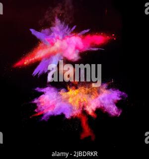 Various multicolored forms of powder paint explode in front of a black background giving off fantastic  exploding clouds of vivid colored powder paint Stock Photo