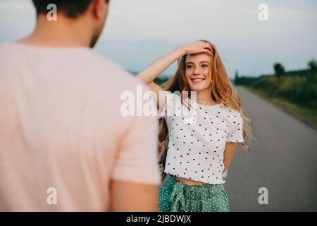 Hiker girl traveling with his boyfriend on country road. Country road in autumn time. Stock Photo
