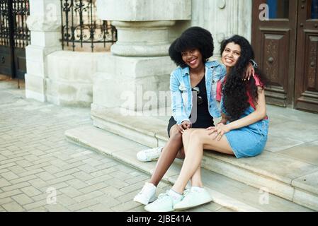 Happy young African American woman smiling, hugging Indian girlfriends and looking at the camera. Multinational friendship concept. Stock Photo