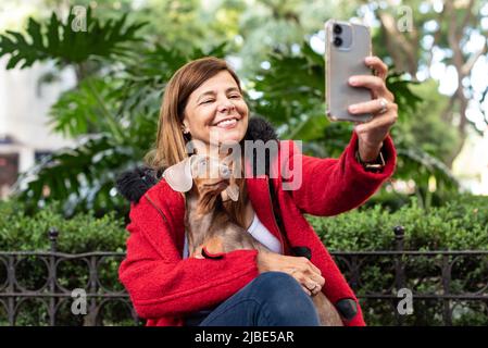 Latin woman holding her dog while taking a selfie of both Stock Photo