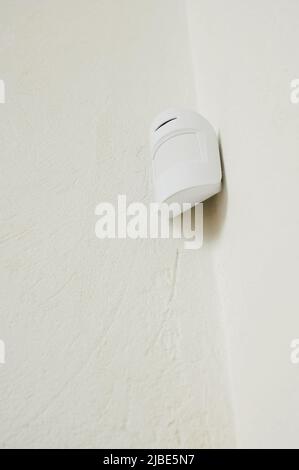 motion sensor in the interior for security, smoke alarm system smart home installed on the wall under the ceiling Stock Photo