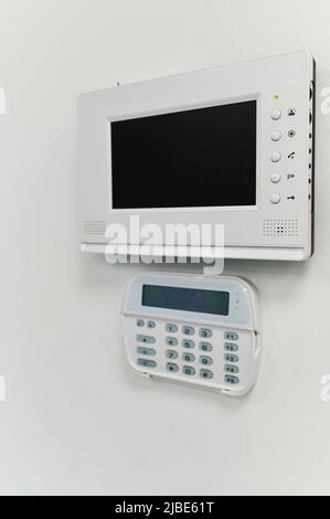 wall-mounted monitor of the video surveillance system in the interior of the office space, remote electronic key for the alarm system and the password Stock Photo