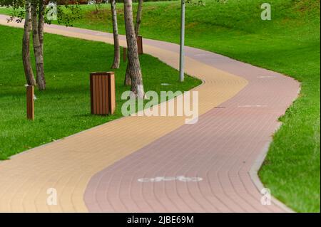 Paving stone paths with colored red and yellow bricks with bicycle markings among greenery, urban landscaping with plants in landscape design, park on Stock Photo