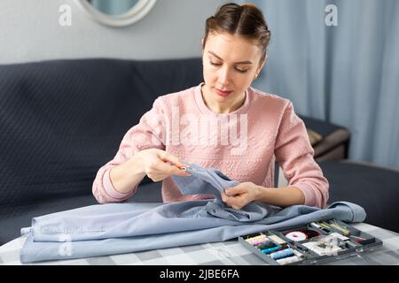 Young woman stitching clothes at home Stock Photo