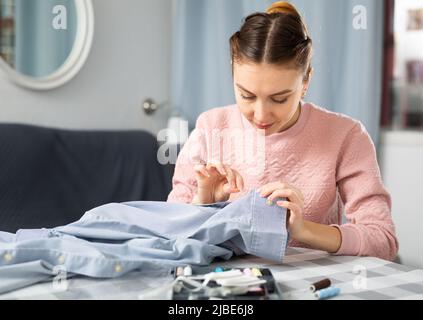 Young woman stitching clothes at home Stock Photo