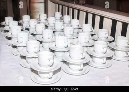 bar at an outdoor ceremony. Lots of cups and saucers on the table. pyramid of cups and saucers for the holiday. Tea cups catering and serving at a ban Stock Photo