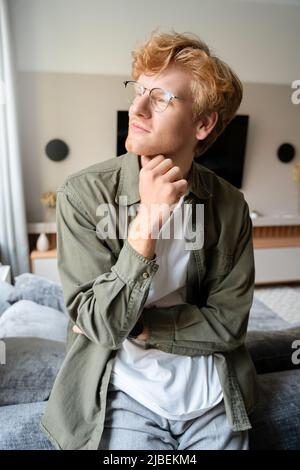 Pensive young ginger irish man in glasses looking forward window portrait Stock Photo