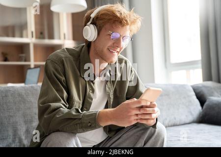 Young irish ginger man in headphone doing video call using smartphone Stock Photo