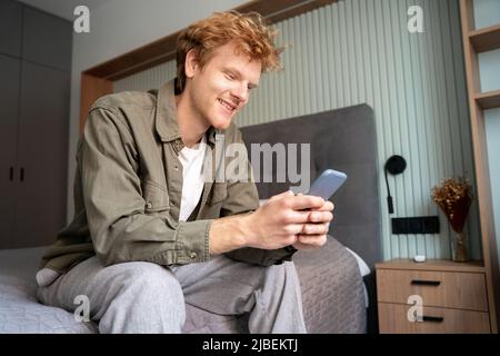 Smiling young adult ginger irish freelance business man using mobile phone Stock Photo