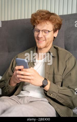 Smiling young ginger british man on virtual communication video call using phone Stock Photo