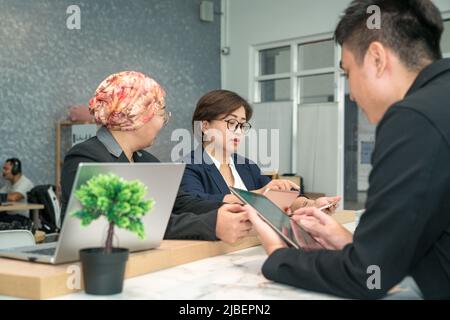Group of Asian business people working together in a modern co working space. Stock Photo