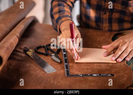 The man working with genuine leather in workshop. Stock Photo