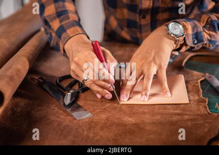 The man working with genuine leather in workshop. Stock Photo