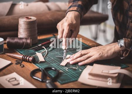 The man working with genuine leather in workshop. Stock Photo