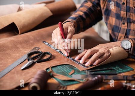 The man working with genuine leather in workshop. Stock Photo