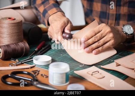 The man working with genuine leather in workshop. Stock Photo
