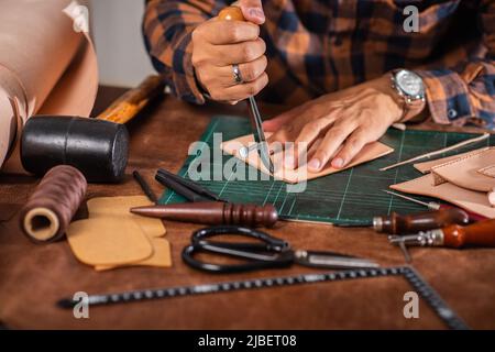 The man working with genuine leather in workshop. Stock Photo