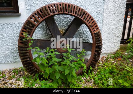 Mill wheel leaning against the house wall Stock Photo