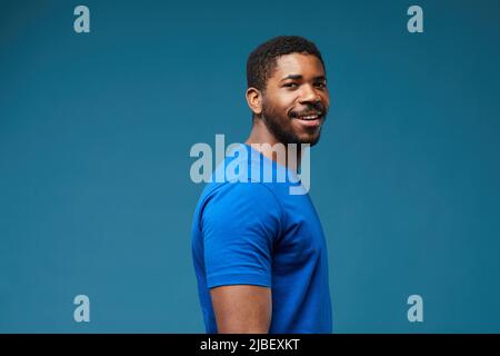 Portrait of smiling black man looking at camera and wearing blue shirt on vibrant blue background, copy space Stock Photo