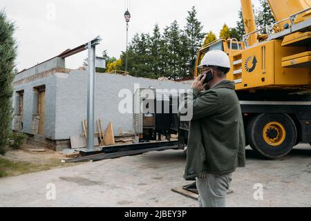 Foreman talking by phone on construction site. architect discussing project using smart phone, construction engineers planning building. Communication Stock Photo